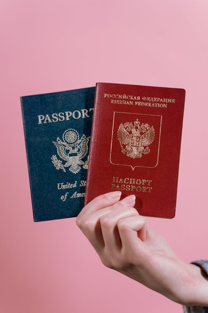 services-img A hand holding US and Russian passports against a pink background.